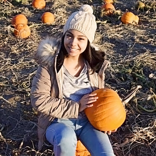 a child sitting in a pumpkin patch