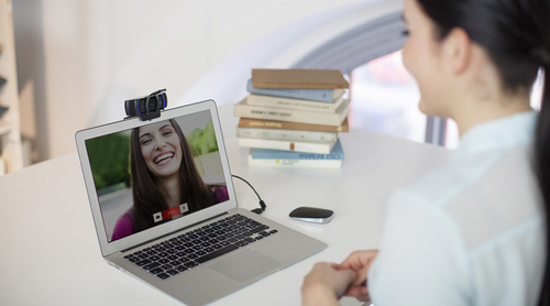 A person at a deck with laptop talking to a friend using a webcam