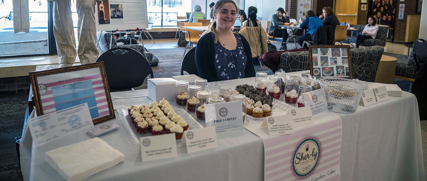 a person standing behind a table with cupcakes