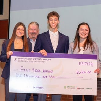 Minnesota State University student winners posing for a group photo with a giant check at the 2023 FutureSolvers Challenge for their Tropical Wine Hub idea