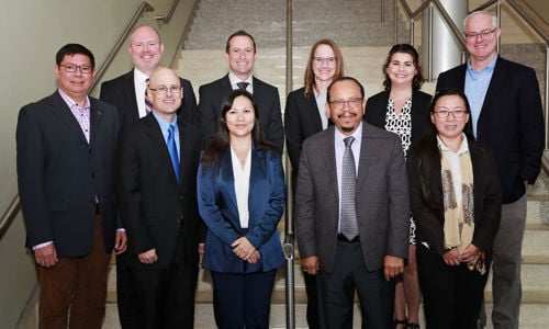 The faculty in the Department of Accounting & Business Law posing for a group photo with stairs behind them on campus