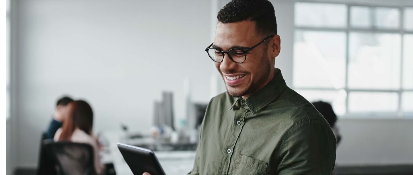 A man looking at a tablet in the office smiling