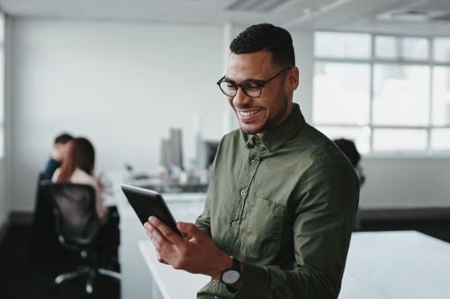 A guy in the office holding a tablet and smiling