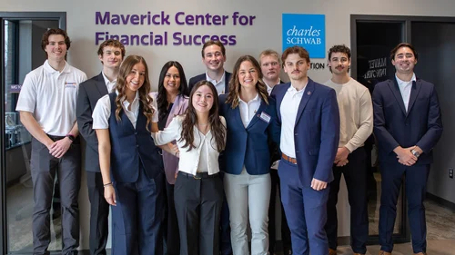 Maverick Center for Financial Success team standing in front of the wall with logo.