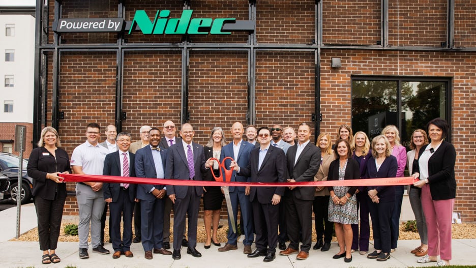 University Administration, faculty and staff posing outside in front of the Maverick Innovation Gateway building holding a red ribbon and giant scissors at the grand opening celebration