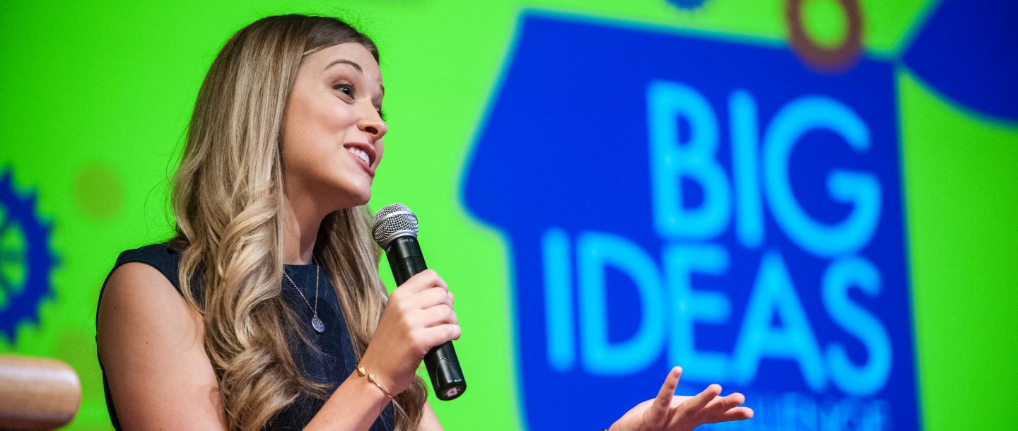 A female on the stage during the Big Ideas competition holding a microphone giving a speech