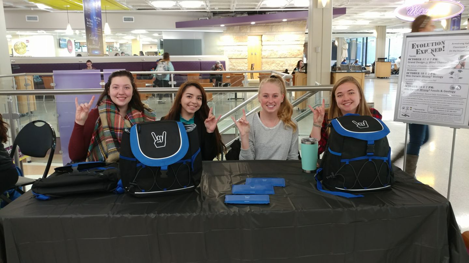 a group of childs sitting at a table with backpacks