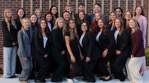 The 2026 Delta Sigma Pi members posing for a group photo outside on campus