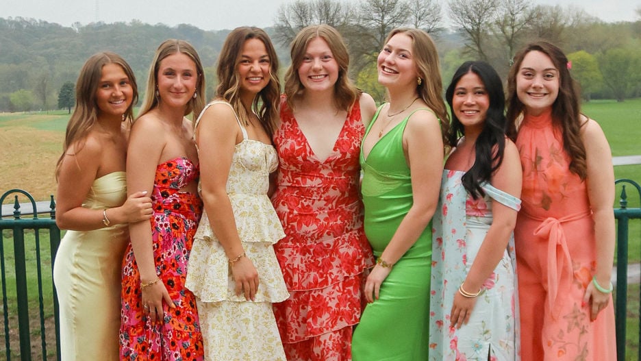 The Women in Business club members posing together outside wearing dresses with smiles